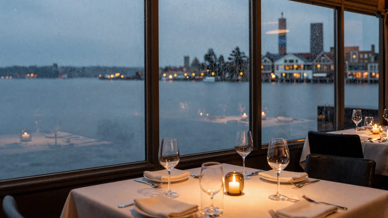 Elegant waterfront restaurant table at dusk with Lake Union view through rain-streaked glass, candle and wine glass