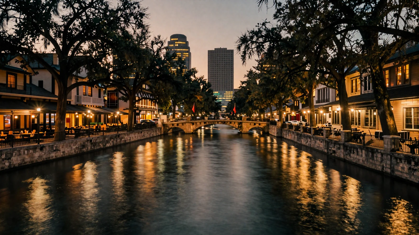 Dusk skyline over the San Antonio River Walk with city lights reflecting on the water